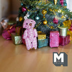 1:12 scale miniature plaid plush bear in pink and white with black nose, sitting by gift boxes under a Christmas tree