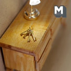 1:12 scale miniature metal key ring with 4 keys in gold, shown on a wood dresser beside a lamp