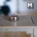 1:12 scale miniature metal cooking pot with lid in polished silver with two side handles, shown on a wood table