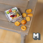 1:12 scale miniature butter cookie tin with 7 loose cookies, printed lid, shown on a rustic wood table