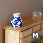 1:12 scale miniature ceramic wide mouth vase with blue floral pattern on white, shown on a wood dresser