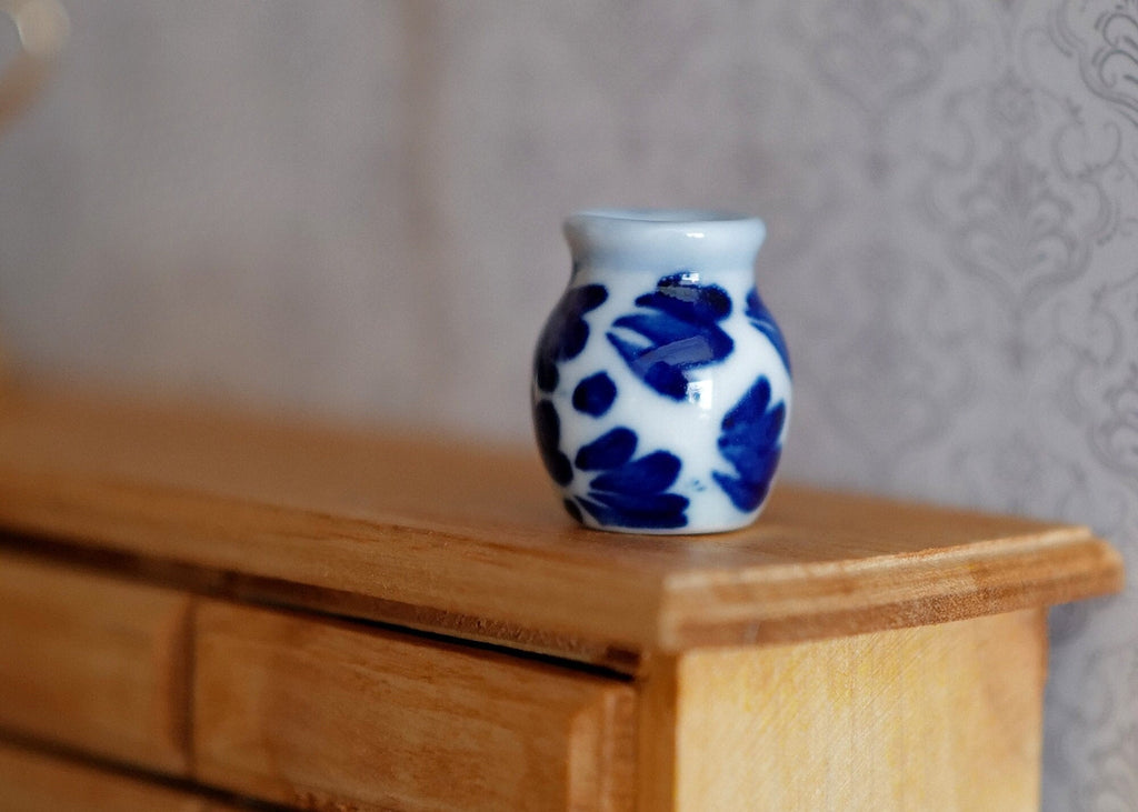 1:12 scale miniature ceramic flower pot with blue floral pattern on white, rounded jar shape, shown on a wood dresser
