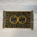 1:12 scale miniature wool medallion area rug in golden yellow with black pattern and gray fringe, on a wood floor