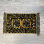 1:12 scale miniature wool medallion area rug in golden yellow with black pattern and gray fringe, on a wood floor