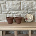 1:12 scale miniature clay flower pots in brown terracotta, set of 2, on a wood shelf beside a coin for scale