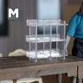 1:12 scale miniature clear acrylic cake display shelf with 3 tiers and scalloped edges, shown on a dark wood table