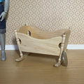 1:12 scale miniature unpainted wood rocking baby cradle with shaped sides and cutout ends, shown beside a coin