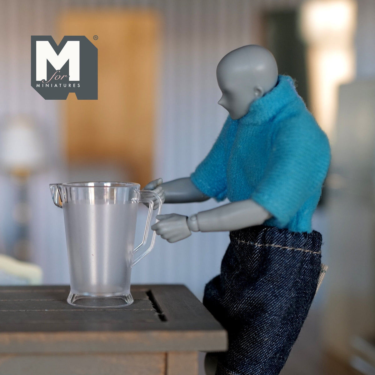 1:12 scale miniature clear beer pitcher with handle, shown on a table with a poseable figure