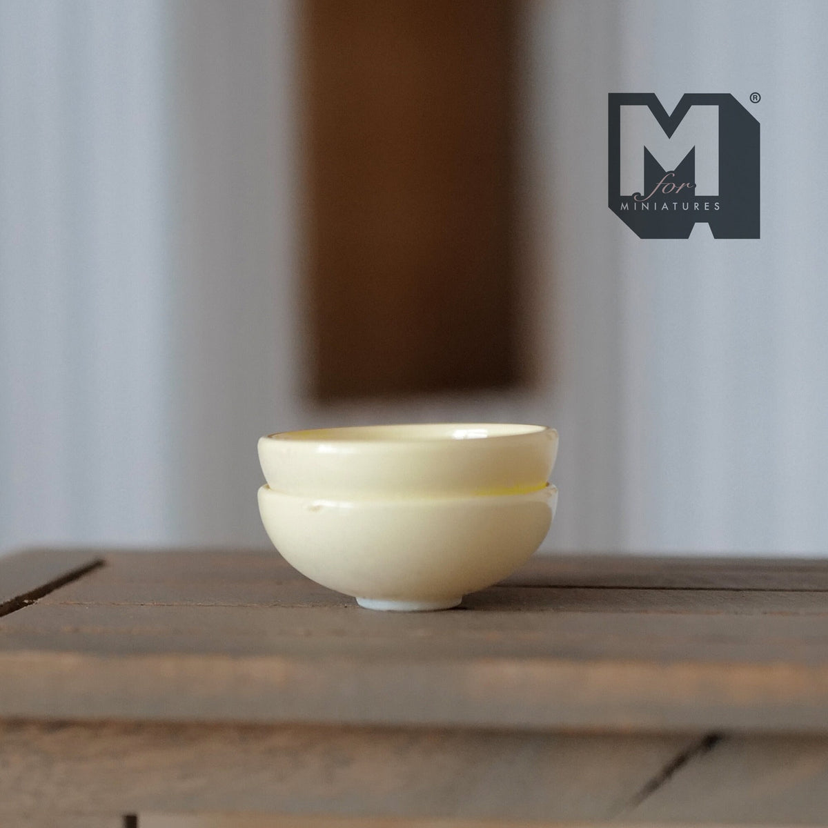 1:12 scale miniature large bowls in cream, set of 2, shown stacked on a dark wood table