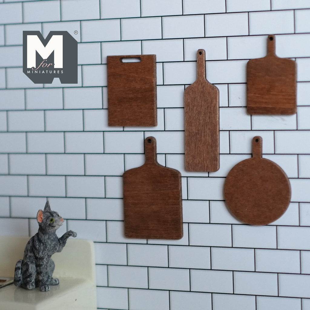 1:12 scale miniature wood cutting boards, set of 5 in assorted shapes, dark brown, shown on a white tile wall