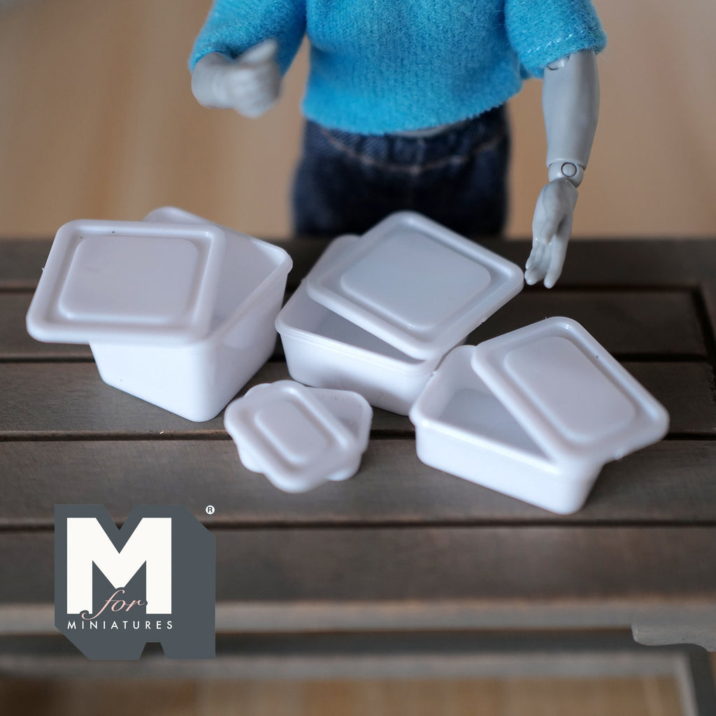 1:12 scale miniature white food containers with lids, set of 4, shown on a dark wood table by a poseable figure
