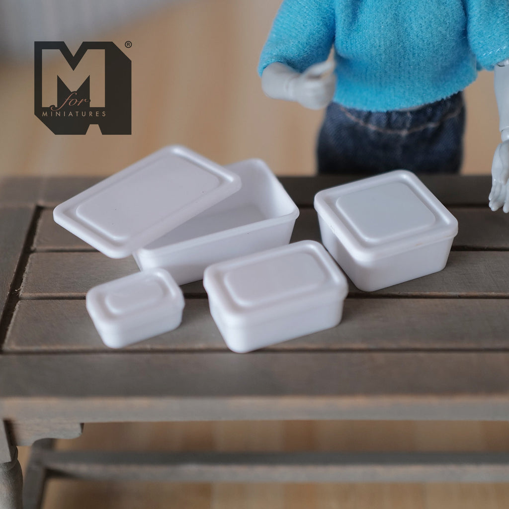 1:12 scale miniature food containers with lids in white, set of 4 sizes, shown on a wood table with an artist figure
