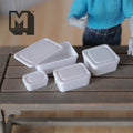 1:12 scale miniature food containers with lids in white, set of 4 sizes, shown on a wood table with an artist figure