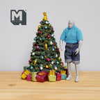 1:12 scale miniature cast resin Christmas tree with ornaments, angel topper and gift boxes, shown beside a figure