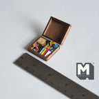1:12 scale miniature wood needlework box with ribbons and thread, hinged lid shown open, beside a ruler for scale