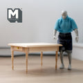 1:12 scale miniature unpainted wood kitchen prep table with 2 side drawers and turned legs, shown beside a figure