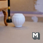 1:12 scale miniature ceramic ribbed round planter in white, shown empty on a floor beside a wood table leg