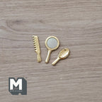 1:12 scale miniature gold hand mirror, comb and hair brush, set of 3, laid out on a wood surface