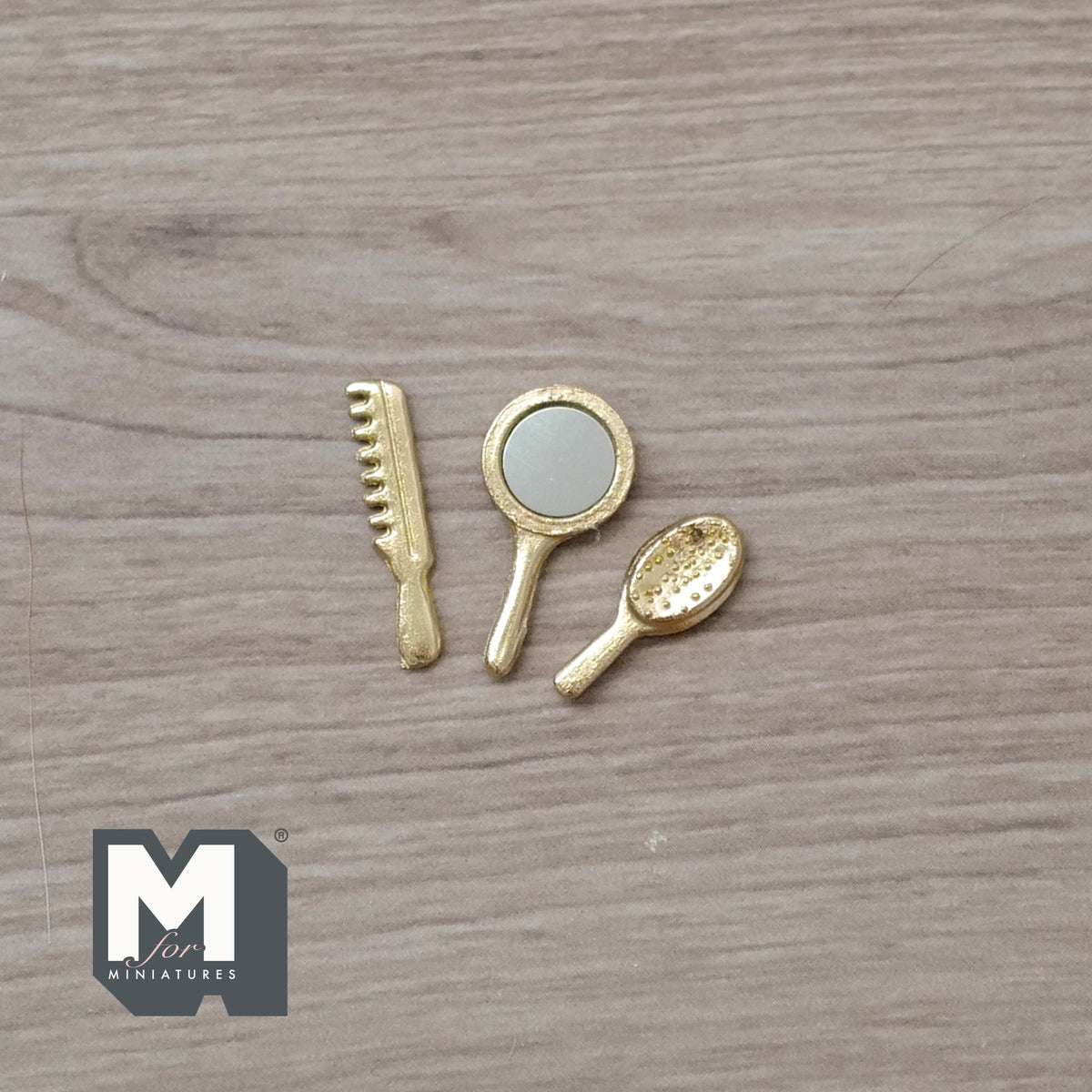 1:12 scale miniature gold hand mirror, comb and hair brush, set of 3, laid out on a wood surface