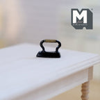 1:12 scale miniature classic flat iron in black with arched handle, shown on a light wood table
