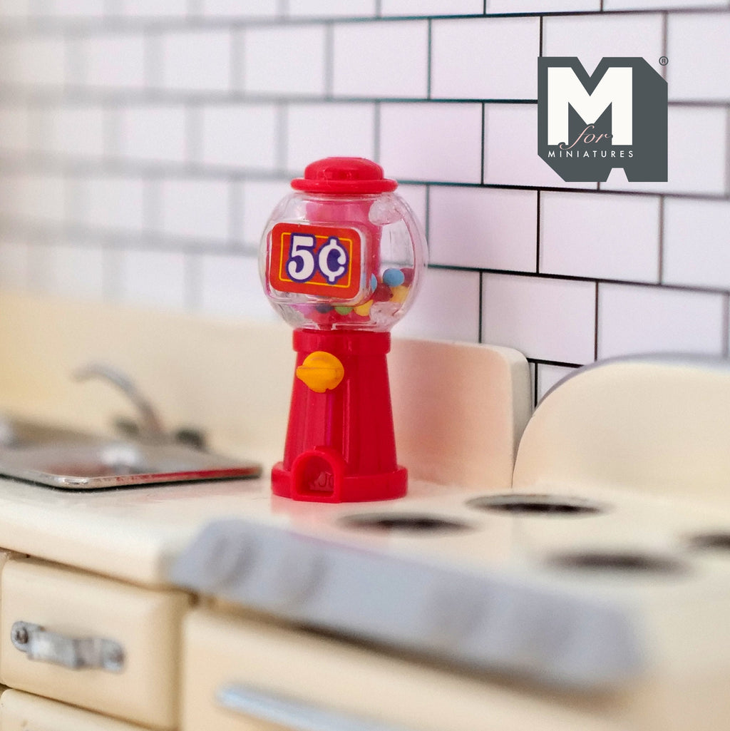 1:12 scale miniature red tabletop gumball machine with clear globe and colorful gumballs, on a kitchen counter
