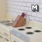 1:12 scale miniature wood knife block with knives, angled block shown on a cream kitchen counter beside a stove
