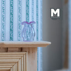 1:12 scale miniature lavender glass vase with flared rim and ribbed body, shown on a wood mantel