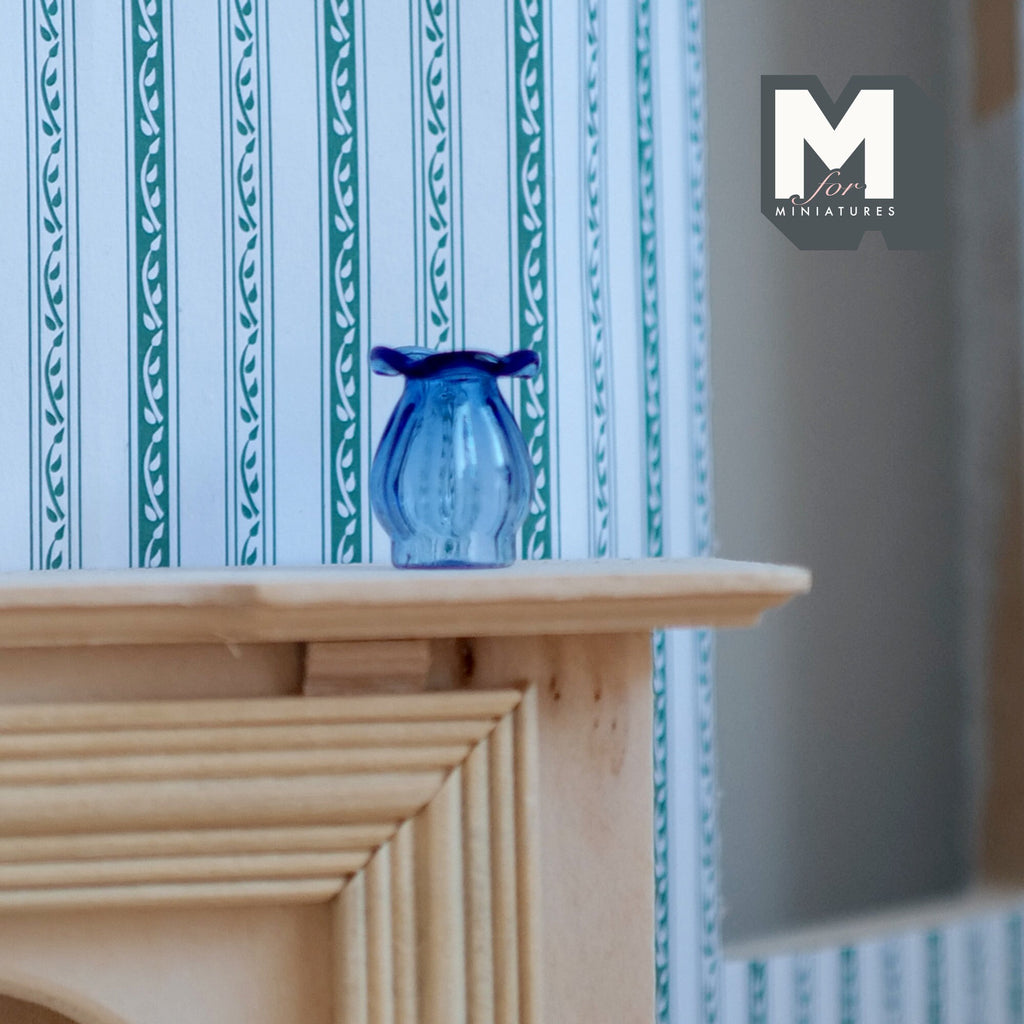 1:12 scale miniature glass vase in blue with flared rim and ribbed body, shown on a wood mantel by striped wallpaper