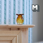 1:12 scale miniature glass vase with flared rim in amber, ribbed translucent body, shown on a wood mantel