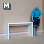 1:12 scale miniature console table in white with slab legs, shown against a wall beside a jointed figure for scale