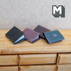 1:12 scale miniature hardcover notebooks with blank pages, set of 4, blue, purple and brown covers, on a wood dresser