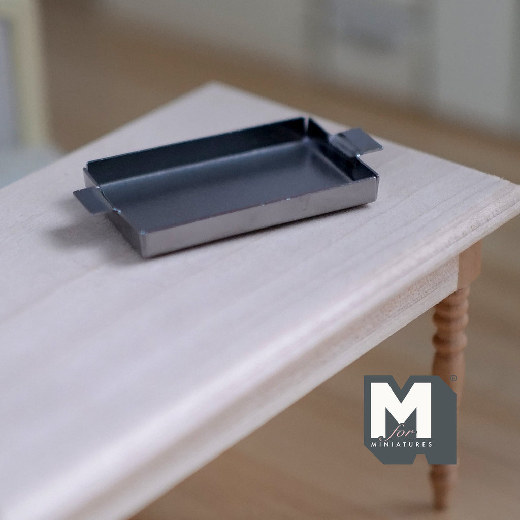 1:12 scale miniature silver metal baking tray with end handles, rectangular, shown on a white wood table