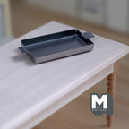 1:12 scale miniature silver metal baking tray with end handles, rectangular, shown on a white wood table