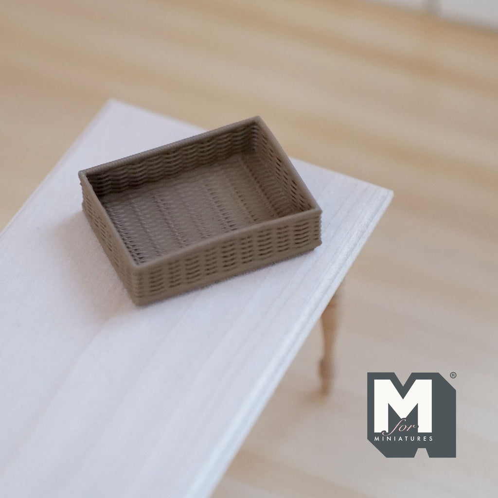 1:12 scale miniature rectangular woven basket in brown with low open sides, shown on a white table