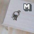 1:12 scale miniature metal keys on ring in antique silver, 3 keys, shown on a light wood surface