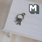 1:12 scale miniature metal keys on ring in antique silver, 3 keys, shown on a light wood surface