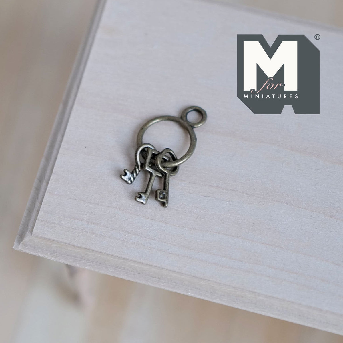 1:12 scale miniature metal keys on ring in antique silver, 3 keys, shown on a light wood surface