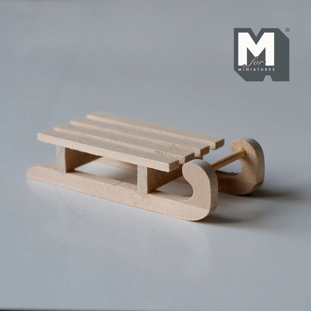 1:12 scale miniature unpainted wood slatted sledge, medium, with curved runners, shown on a gray surface