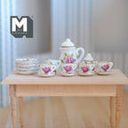 1:12 scale miniature porcelain tea set with pink flowers and green leaves, set of 15, shown on a wood table