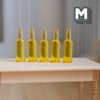 1:12 scale miniature cast resin beer bottles in amber yellow, set of 5, shown lined up on a bare wood table