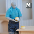 1:12 scale miniature cast resin bread buns, set of 2, golden round rolls, one held by a poseable figure at a wood table