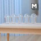 1:12 scale miniature clear cups with dome lids, set of 5, shown lined up on a bare wood table