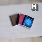 1:12 scale miniature hardcover books in brown, red and blue with printed covers, set of 3, shown on a wood table