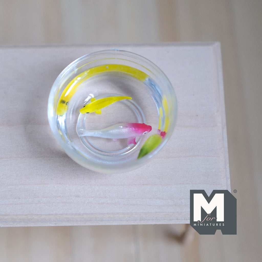 1:12 scale miniature glass fish bowl with 2 fish, one red and white and one yellow, in clear water on a white wood table