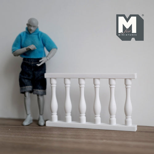 1:12 scale miniature balustrade panel in white with turned spindles and top rail, shown beside a jointed figure