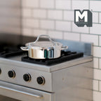 1:12 scale miniature metal cooking pot with lid in polished silver, two side handles, shown on a kitchen stove