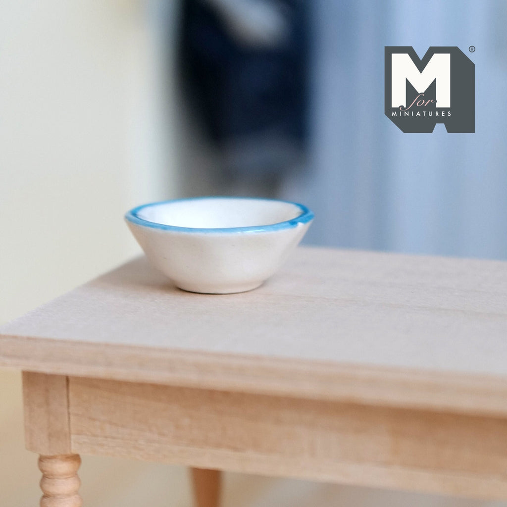 1:12 scale miniature ceramic bowl in white with light blue rim, shown on a light wood table