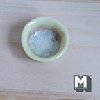 1:12 scale miniature light yellow ceramic bowl with crackle glaze center, top view on a wood surface