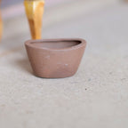 1:12 scale miniature clay oval flower pot in brown with a matte finish, shown empty on a light gray floor