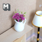 1:12 scale miniature pink carnations in a white ceramic pitcher vase, shown on a wood mantel beside a lamp